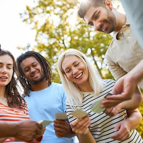 Groupe d'adultes souriants manipulant des cartes de jeu en plein air